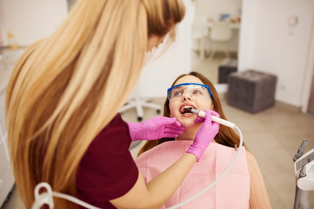 Little girl in protective glasses visiting dentist in clinic. Conception of stomatology
